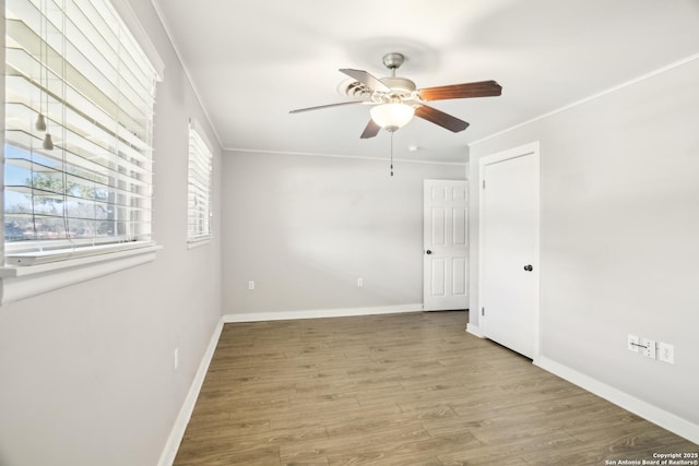 unfurnished room with ceiling fan, baseboards, wood finished floors, and crown molding