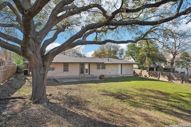 rear view of property with a patio, a yard, a fenced backyard, and brick siding