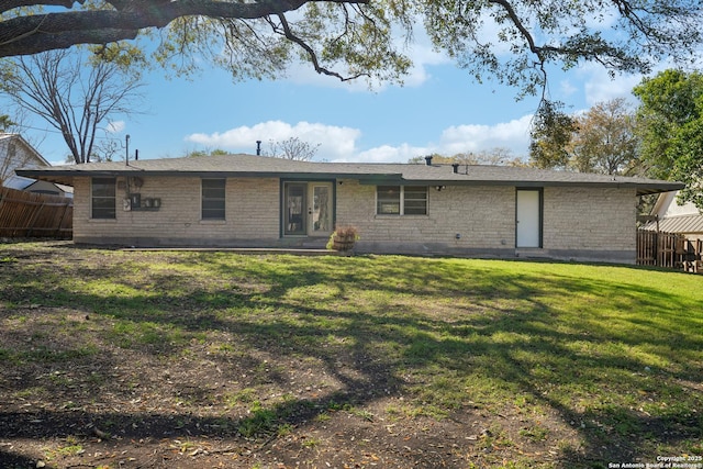 rear view of house with a lawn, brick siding, and fence