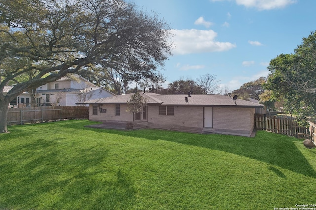 back of property featuring a fenced backyard, brick siding, and a yard