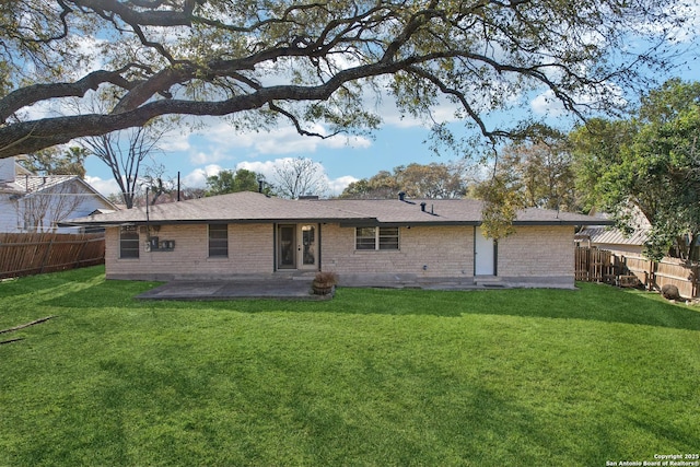 rear view of house featuring a patio area, a yard, a fenced backyard, and brick siding