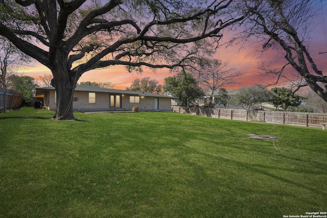 yard at dusk with central AC unit and fence