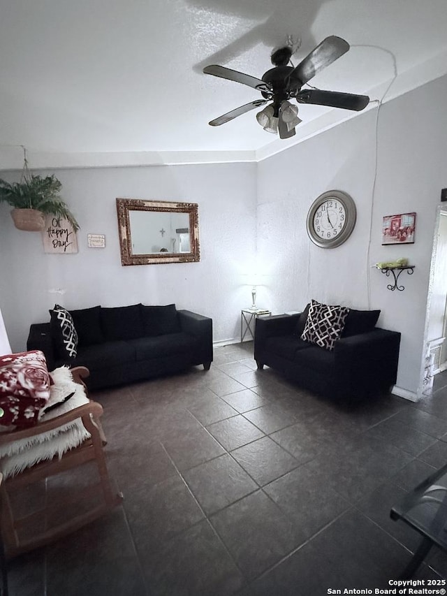 living area with baseboards, dark tile patterned floors, and a ceiling fan