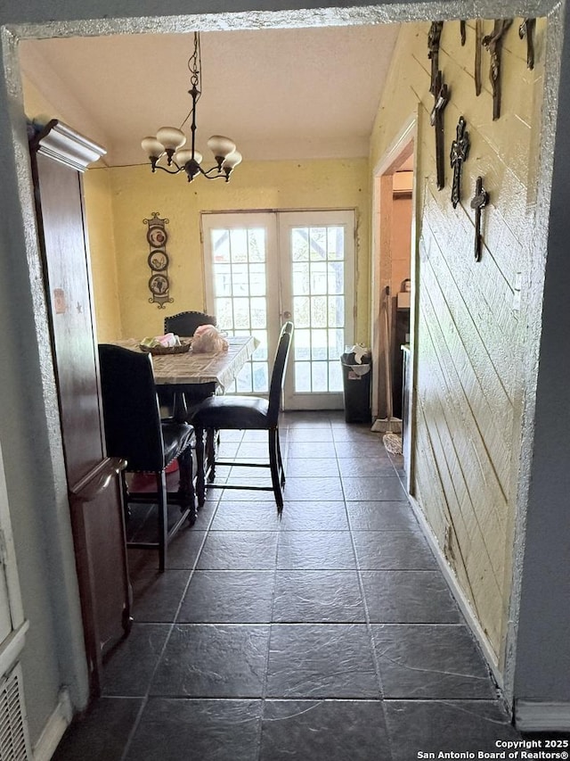 dining room with a notable chandelier, baseboards, and stone tile flooring