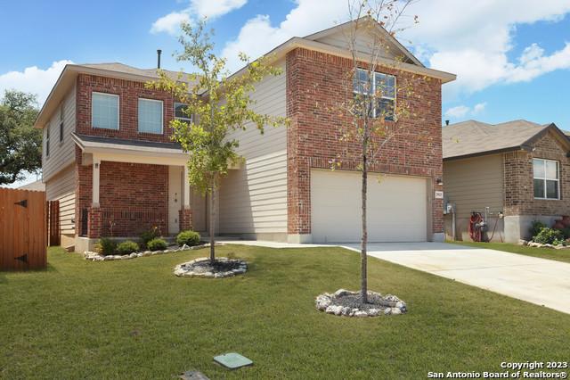 traditional-style house with a front yard, an attached garage, fence, and brick siding