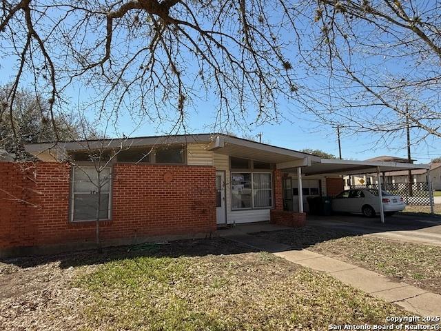 view of side of property featuring brick siding, concrete driveway, and a carport