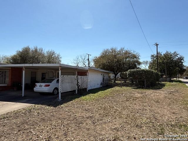 view of side of home featuring an attached carport, concrete driveway, and fence