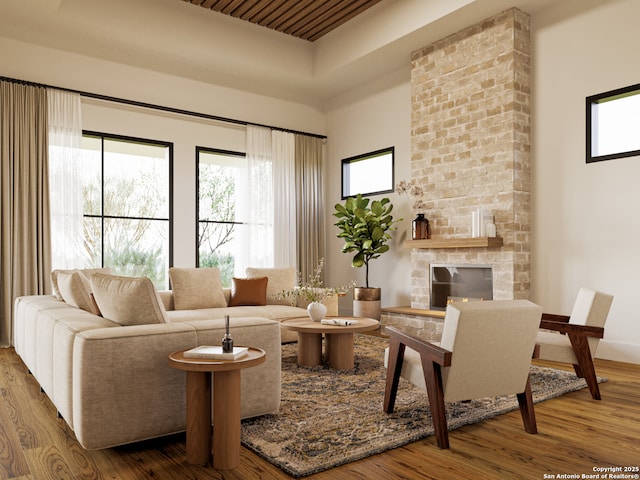 living room with a high ceiling, a stone fireplace, and wood finished floors