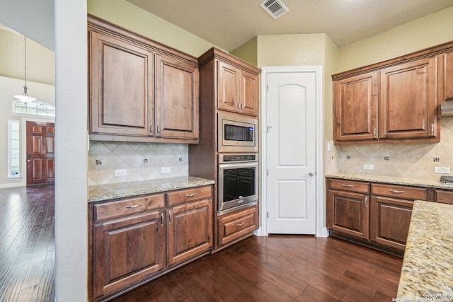 kitchen with dark wood finished floors, light stone counters, visible vents, and stainless steel appliances