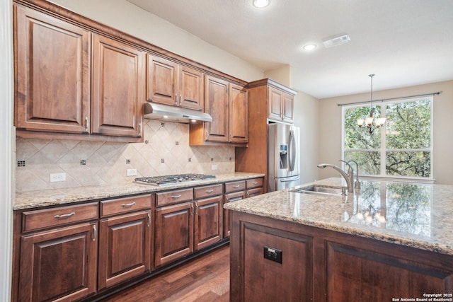 kitchen with visible vents, light stone countertops, under cabinet range hood, appliances with stainless steel finishes, and a sink