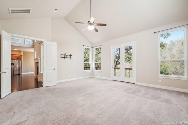 carpeted spare room featuring a healthy amount of sunlight, visible vents, and high vaulted ceiling