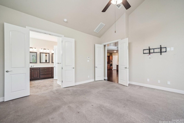 unfurnished bedroom featuring ensuite bath, light colored carpet, high vaulted ceiling, and baseboards