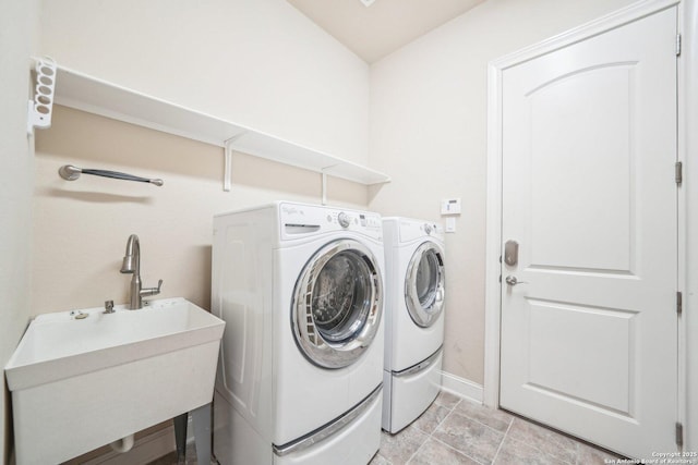 laundry room featuring laundry area, washing machine and dryer, baseboards, and a sink