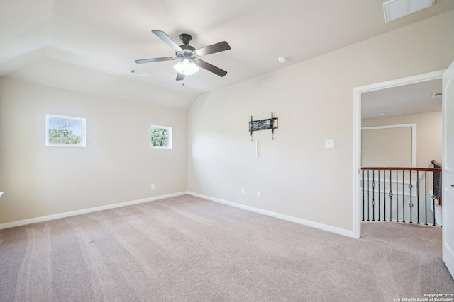 empty room with visible vents, light carpet, lofted ceiling, and baseboards