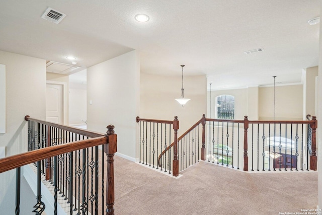 hallway with visible vents, baseboards, attic access, carpet floors, and an upstairs landing