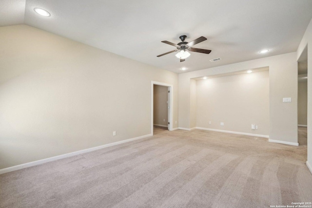 spare room featuring visible vents, baseboards, vaulted ceiling, light carpet, and a ceiling fan