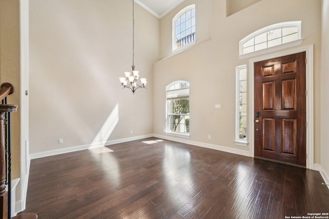 foyer entrance featuring dark wood-type flooring, baseboards, a towering ceiling, and a chandelier