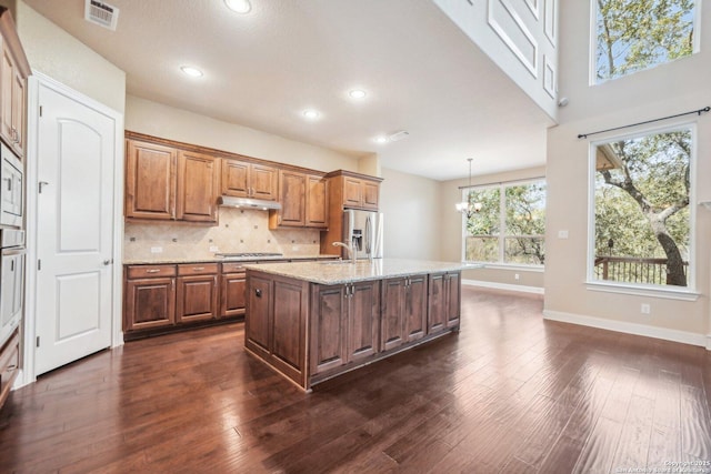 kitchen with visible vents, a kitchen island with sink, stainless steel appliances, under cabinet range hood, and backsplash