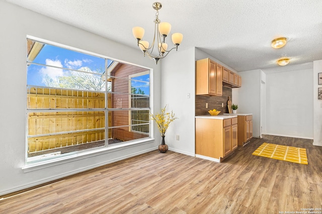 kitchen featuring light wood finished floors, backsplash, and a textured ceiling