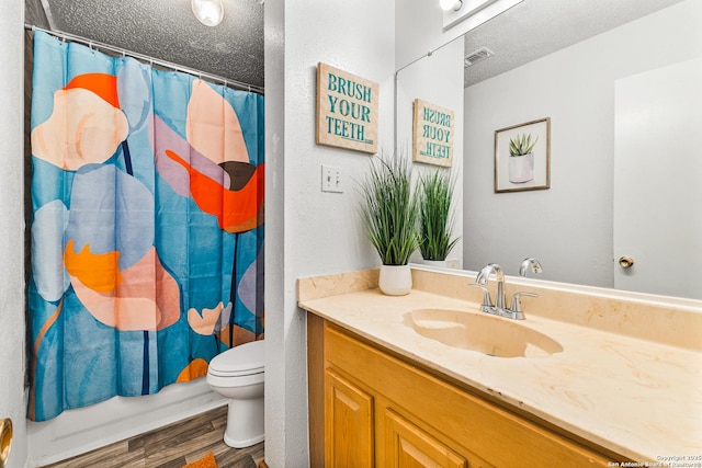 bathroom featuring vanity, toilet, wood finished floors, and a textured ceiling