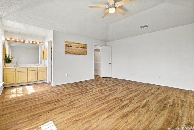 unfurnished bedroom with a spacious closet, visible vents, baseboards, ensuite bathroom, and light wood-style floors