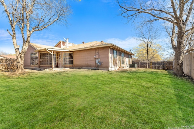 back of property with a lawn, a fenced backyard, a chimney, and a sunroom