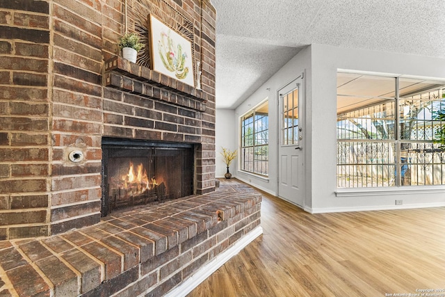 interior space with wood finished floors, a fireplace, baseboards, and a textured ceiling