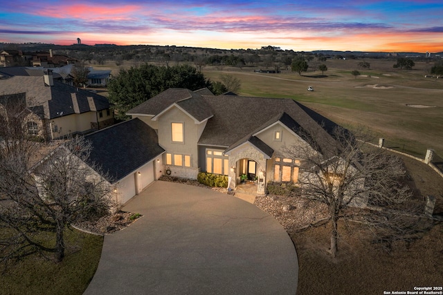 view of front of house with concrete driveway, roof with shingles, stucco siding, a garage, and stone siding