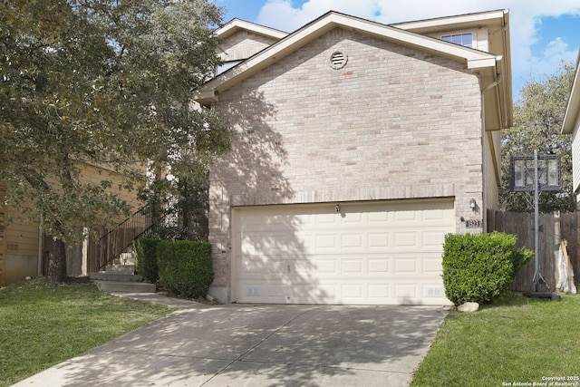 view of front of home with driveway, brick siding, an attached garage, and a front lawn