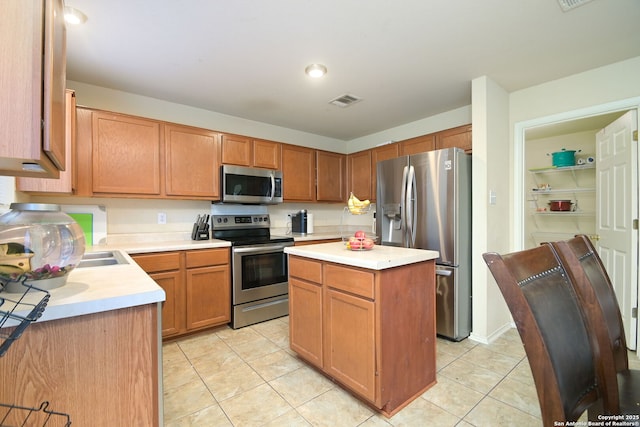 kitchen featuring visible vents, a center island, light countertops, light tile patterned floors, and appliances with stainless steel finishes