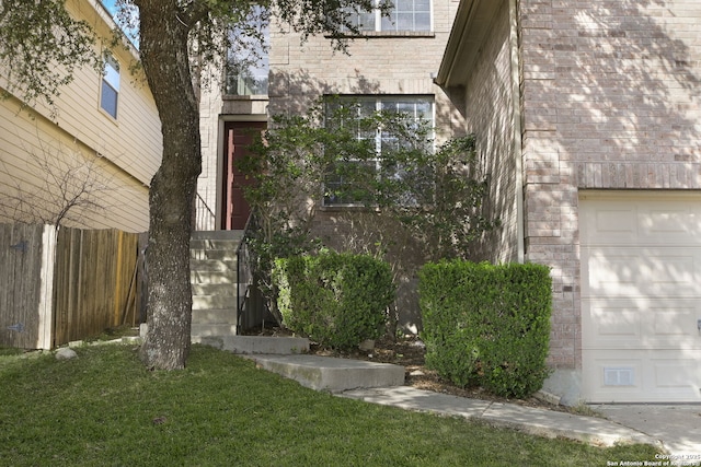 exterior space featuring brick siding, a garage, a yard, and fence