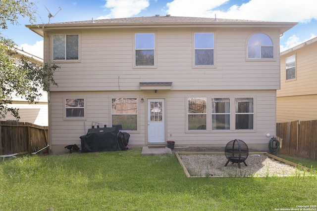 rear view of house featuring a yard, a fire pit, and a fenced backyard