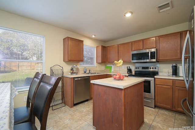 kitchen featuring visible vents, a sink, a kitchen island, appliances with stainless steel finishes, and light countertops