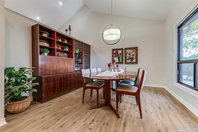 dining room with light wood-type flooring, baseboards, and high vaulted ceiling