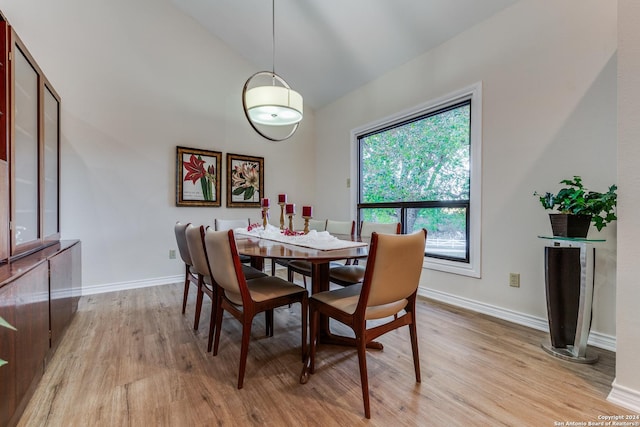 dining space featuring baseboards, high vaulted ceiling, and light wood finished floors