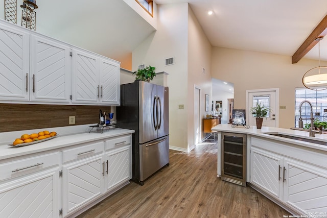 kitchen with visible vents, beverage cooler, wood finished floors, freestanding refrigerator, and white cabinets