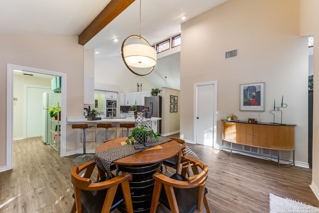 dining area featuring visible vents, beamed ceiling, baseboards, and wood finished floors