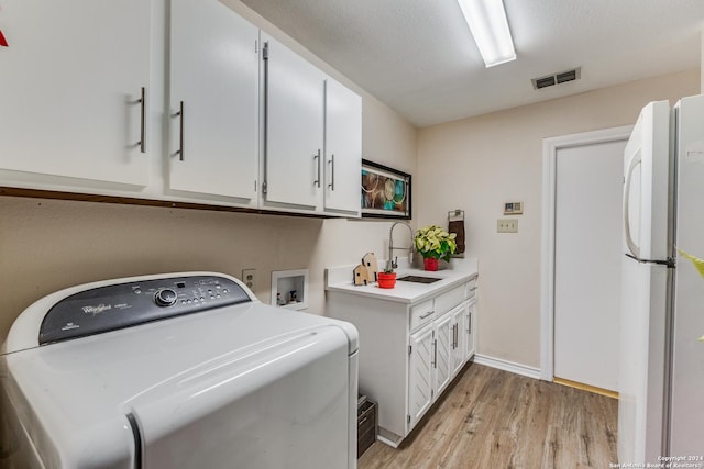 laundry room featuring visible vents, light wood-style flooring, washer / clothes dryer, and a sink