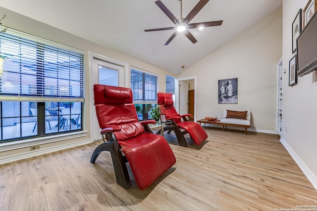 living area with ceiling fan, high vaulted ceiling, baseboards, and wood finished floors