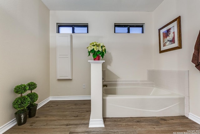 full bathroom with baseboards, a garden tub, and wood finished floors