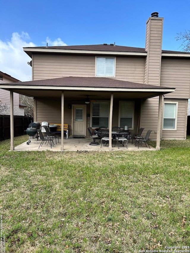 back of house featuring fence, a patio area, a lawn, and a chimney