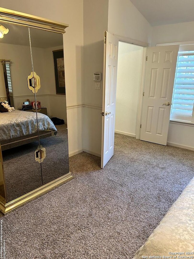 bedroom featuring lofted ceiling, carpet flooring, baseboards, and a closet