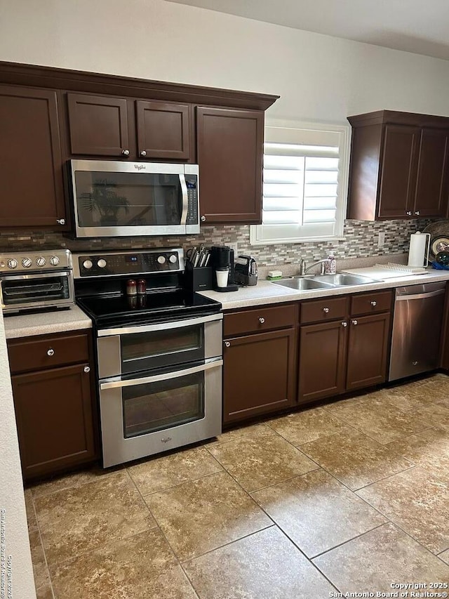 kitchen featuring a sink, stainless steel appliances, dark brown cabinetry, and backsplash