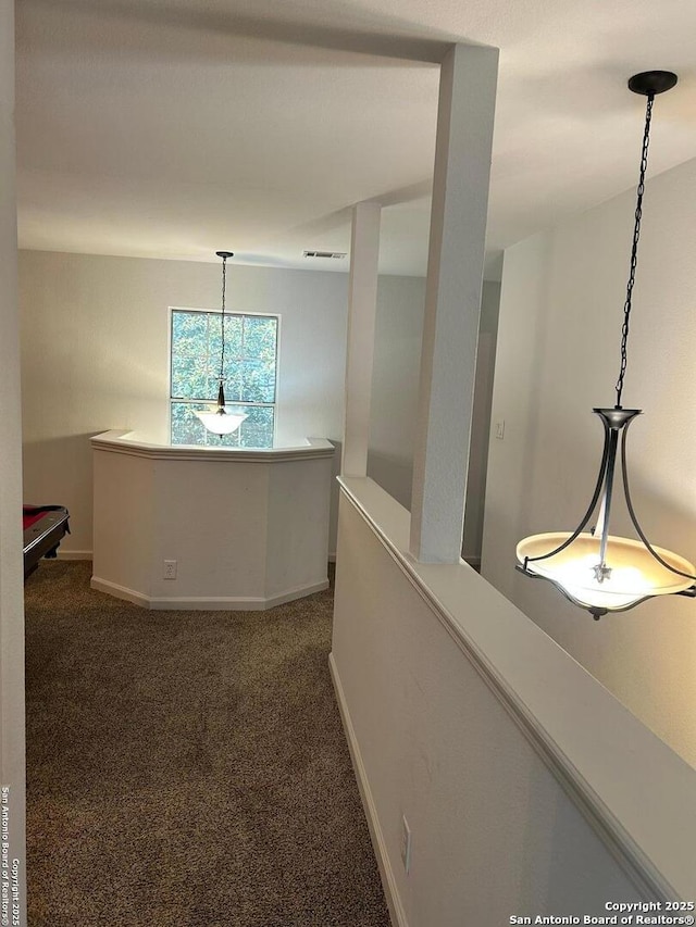 hallway with dark colored carpet, visible vents, and baseboards