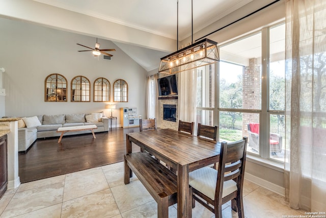 dining space featuring ceiling fan, baseboards, ornamental molding, light tile patterned floors, and a fireplace