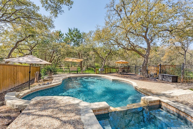 view of pool with a patio area, a pool with connected hot tub, outdoor dining area, and a fenced backyard