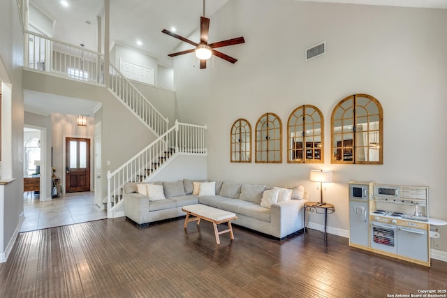 living room featuring stairway, wood finished floors, visible vents, baseboards, and ceiling fan