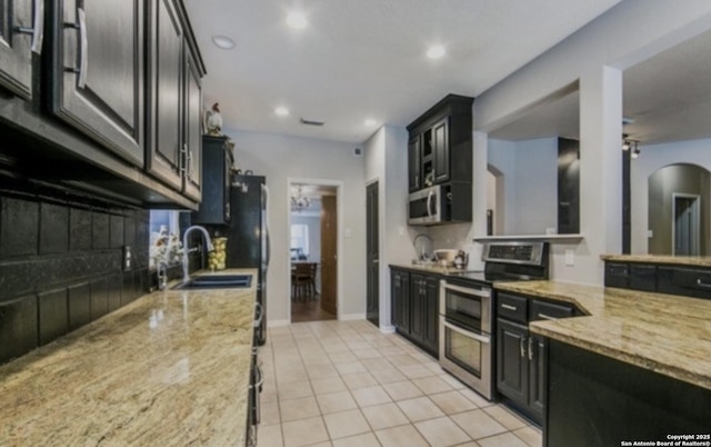 kitchen with light stone counters, light tile patterned flooring, dark cabinets, and stainless steel appliances