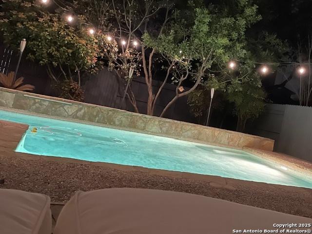 pool at twilight featuring a fenced backyard and an outdoor pool