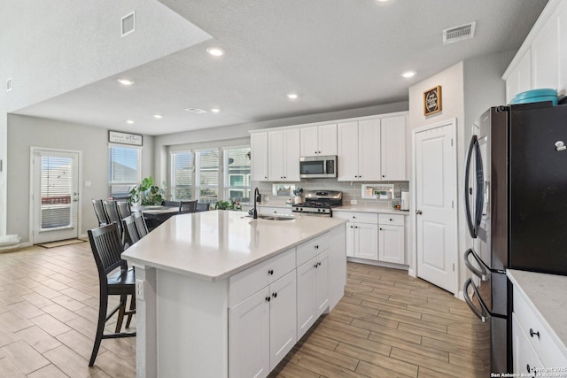 kitchen featuring visible vents, appliances with stainless steel finishes, light countertops, and a sink